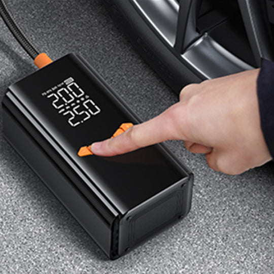 nomade Gonfleur de Pneu & Booster de Batterie Voiture Portable 2-en-1 numérique, avec une main appuyant sur un bouton à l’intérieur d’une voiture
