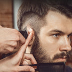 Barbier taillant la barbe d’un client avec un peigne et une Kersens Tondeuse à Cheveux en gros plan
