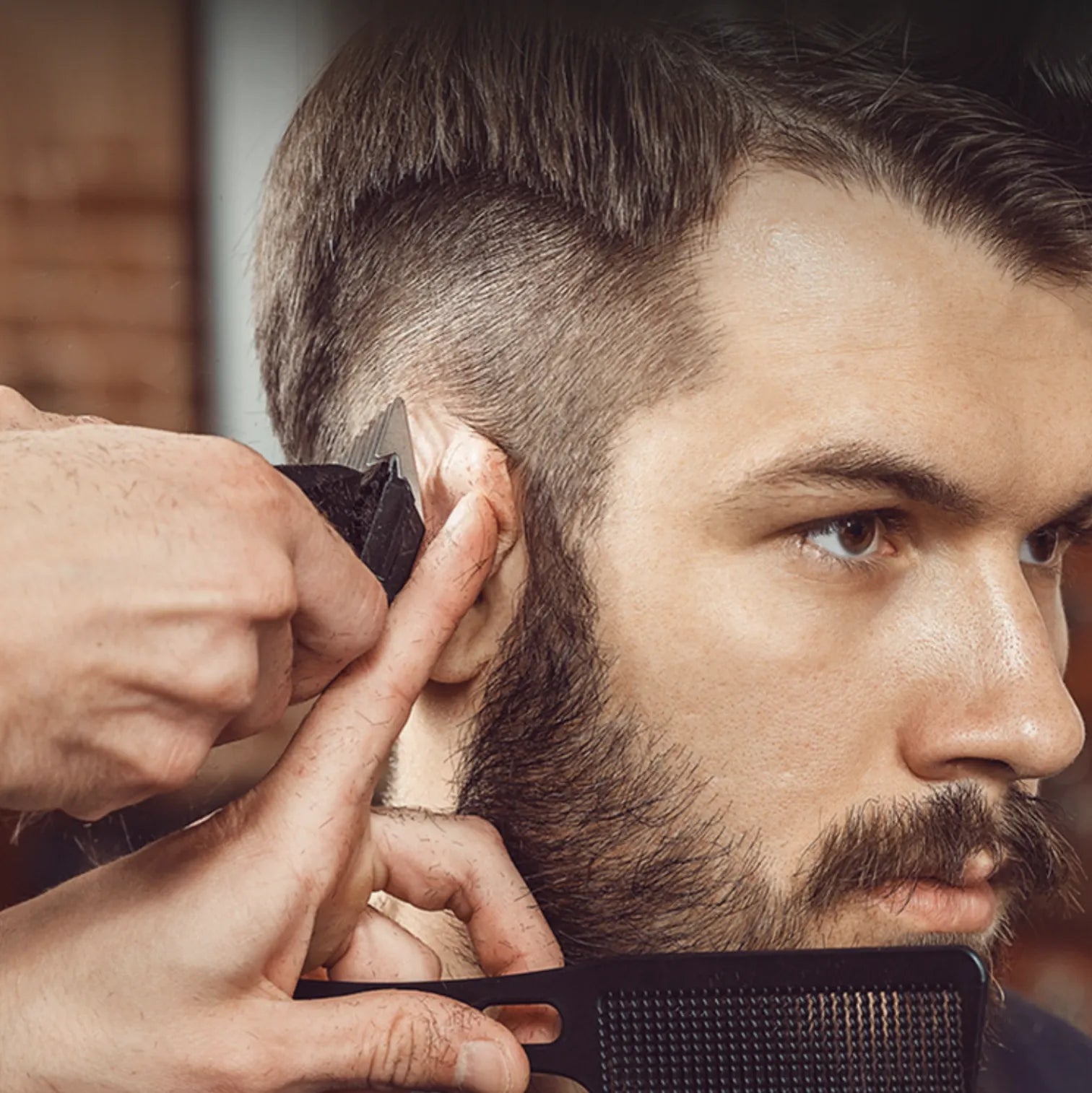Barbier taillant la barbe d’un client avec un peigne et une Kersens Tondeuse à Cheveux en gros plan